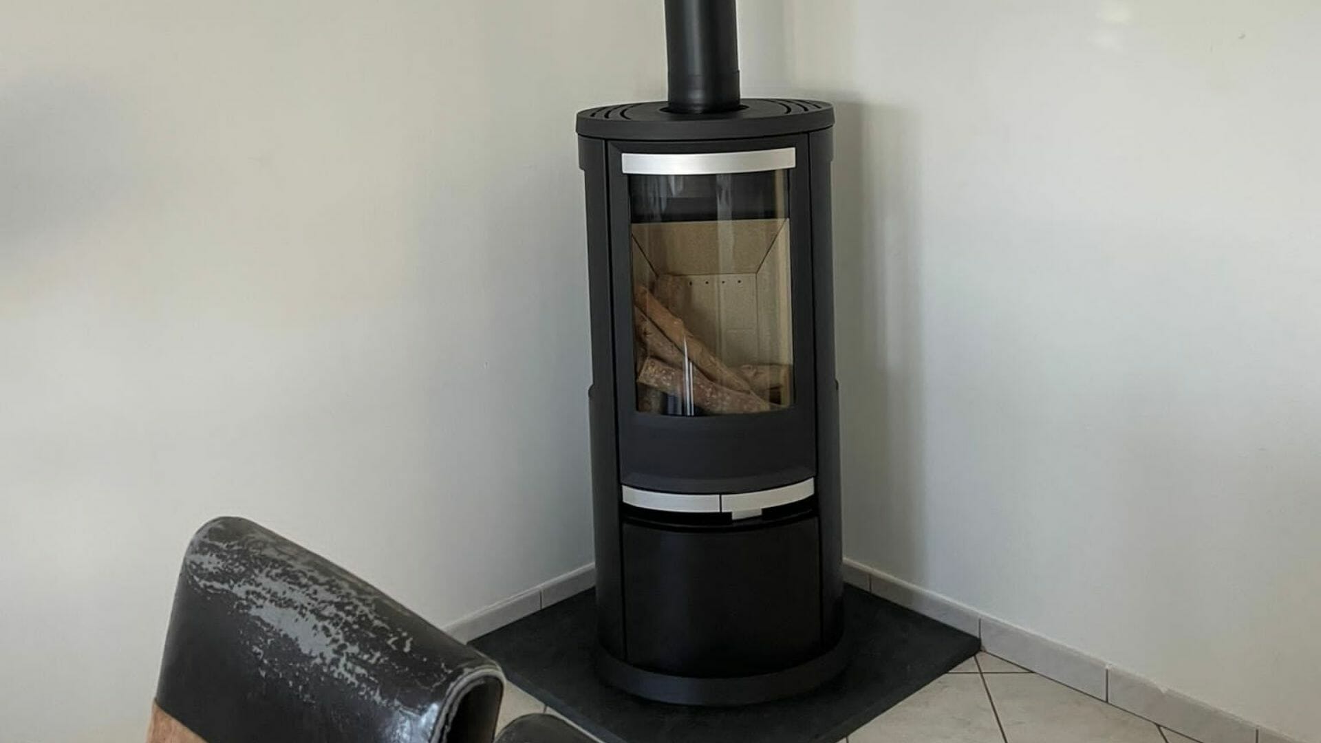 Poêle rond HETA élégamment posé en angle, installé à Arras, Hauts-de-France Poêle à bois FRAM moderne installé dans un salon spacieux par HOMZA, Hauts de France