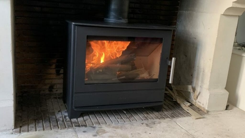 Poêle à bois HETA sur quatre pieds, conçu pour s'encaster parfaitement dans un foyer existant Installation élégante d'un poêle à bois HETA par HOMZA dans une maison traditionnelle des Hauts de France.