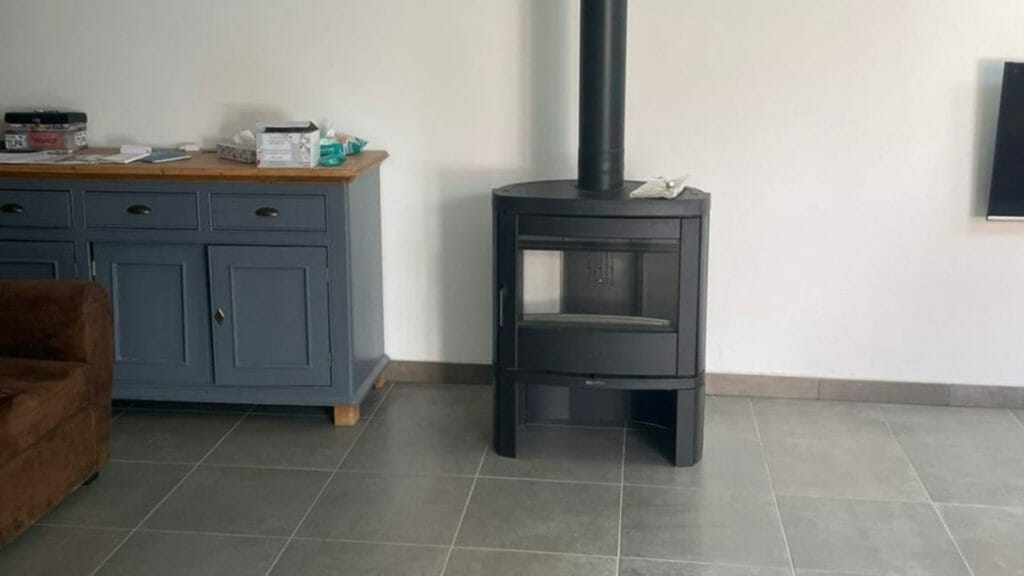 Poêle à bois HETA sur quatre pieds, de faible hauteur, design compact Poêle à bois HETA avec design contemporain, parfaitement intégré dans un intérieur moderne, installation HOMZA.