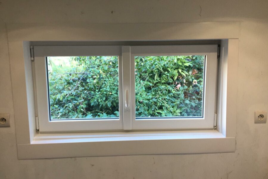Installation d'une petite fenêtre PVC blanche dans une chambre